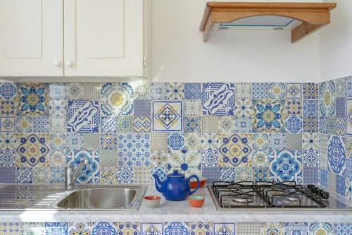 kuchnia z niebiesko-białymi kafelkami na ścianie w obiekcie sole chiaro home w mieście Procida