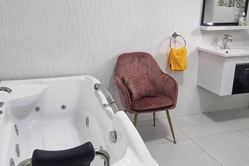 een badkamer met een bad, een stoel en een wastafel bij InstaHomes by Tru - Villa in Blantyre