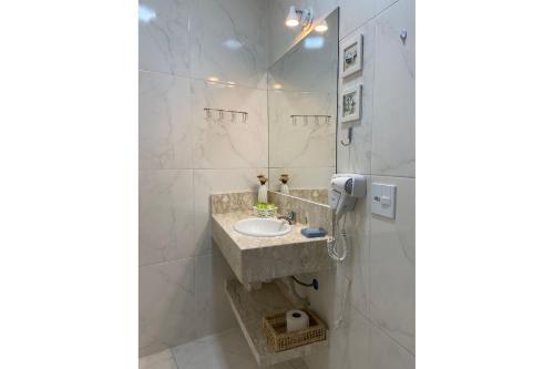 y baño con lavabo y espejo. en Estúdio moderno ÓTIMA LOCALIZAÇÃO Pitangueiras, en Guarujá