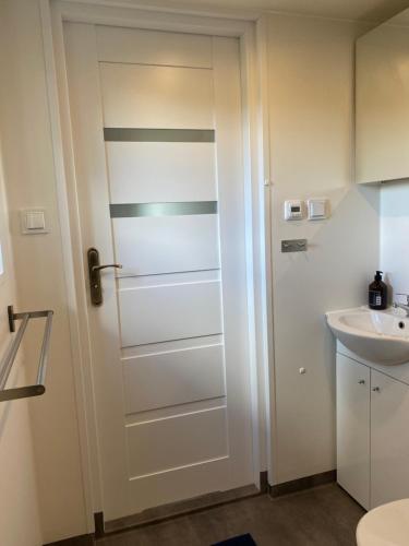 a bathroom with a white door next to a sink at Kattalängan - Lilla huset in Brösarp