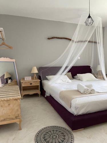 a bedroom with a bed with a mosquito net at Eco Beach And Magic Garden Hotel in Gennadi
