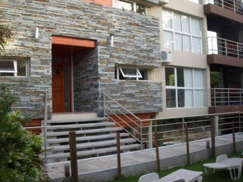 a stone building with stairs and a red door at EL GAVION a 150 m de playa in Mar Azul