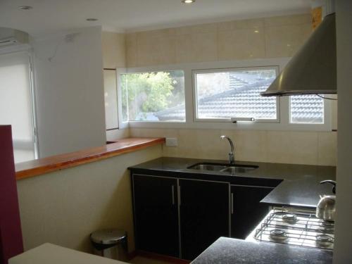a kitchen with a sink and two windows in it at EL GAVION a 150 m de playa in Mar Azul