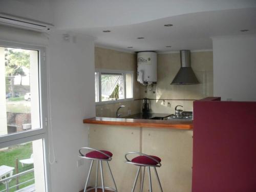 a kitchen with two red stools in front of a counter at EL GAVION a 150 m de playa in Mar Azul