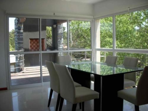 a dining room with a glass table and white chairs at EL GAVION a 150 m de playa in Mar Azul