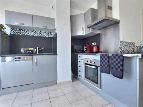 a kitchen with white cabinets and gray appliances at Le CONTI Proche Roissy - Astérix- Gare in Le Plessis-Belleville