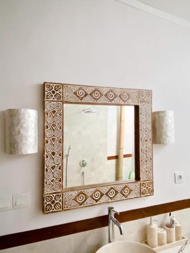 a mirror on a wall above a sink at 2BR Art Villa Bingin in Uluwatu