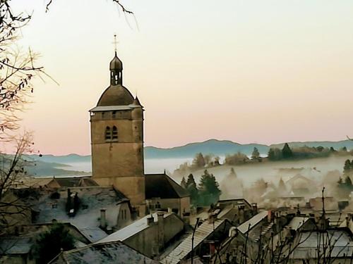 vista su una città con torre della chiesa nella nebbia di Appartement La Bernardine au coeur du Jura a Orgelet