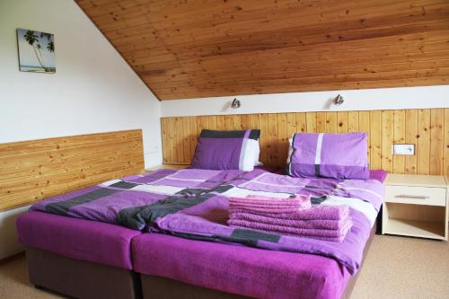 a large purple bed in a room with wooden ceilings at Apartmány Fialka in Kašperské Hory