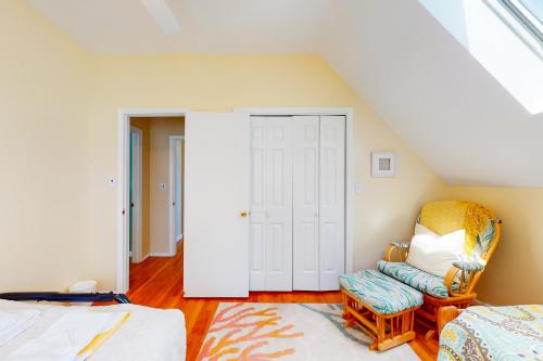 a attic bedroom with a bed and a chair at Sunny Side Up in Oak Bluffs