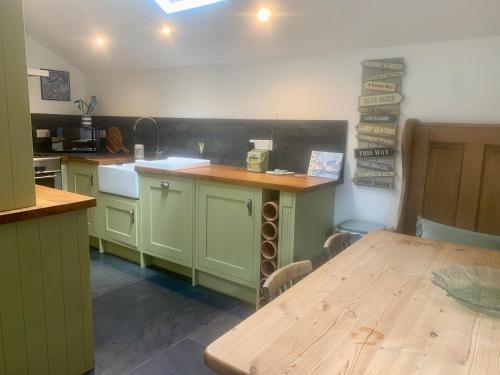 a kitchen with green cabinets and a wooden table at Neptunes Rest in St Austell