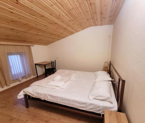 Homelike B&B في تبليسي: سرير في غرفة ذات سقف خشبي