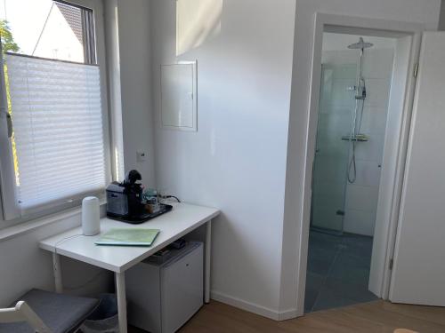 La salle de bains est pourvue d'un bureau blanc et d'une douche. dans l'établissement Messezimmer nahe der Düsseldorfer Messe mit eigenem Eingang und gratis Minibar, à Düsseldorf