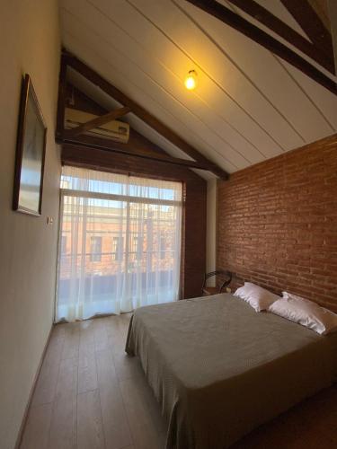 1 dormitorio con cama y pared de ladrillo en DUPLEX A PASOS DE PLAZA URQUIZA en San Miguel de Tucumán