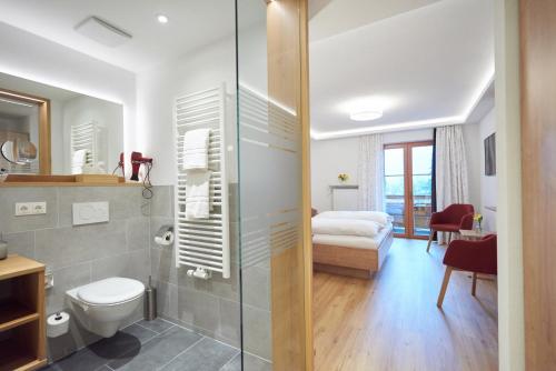 a bathroom with a shower and a toilet and a bedroom at Hotel Georgenhof in Schönau am Königssee