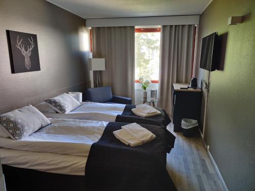 Habitación de hotel con 2 camas y TV en Ellivuori, Ellin Pooli 1, en Sastamala