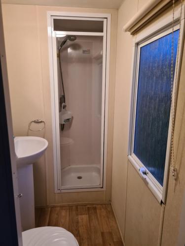 een badkamer met een douche, een toilet en een wastafel bij Cosy, family caravan near the beach in Clacton-on-Sea