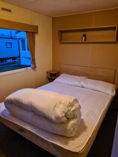 een slaapkamer met een wit bed en een raam bij Cosy, family caravan near the beach in Clacton-on-Sea