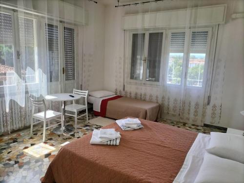 een slaapkamer met 2 bedden en een tafel en ramen bij Affittacamere Mark in Faenza