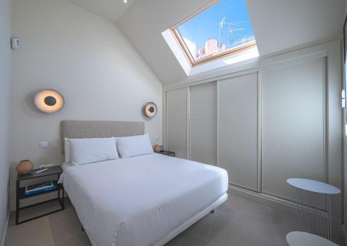 um quarto com uma cama branca e uma clarabóia em Málaga Centro Terraza 4-D em Málaga