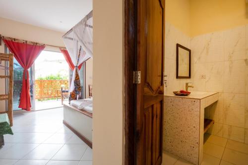 a bathroom with a sink and a room with a window at Villa RaCoCo in Jambiani