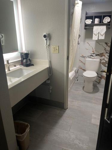 a bathroom with a sink and a toilet and a phone at HomeTown Inn and Suites Belle Plaine in Belle Plaine