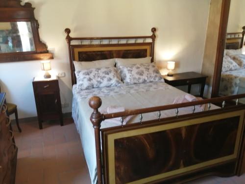 1 dormitorio con 1 cama de madera y 2 mesitas de noche en LA BOTTEGA DEL CALZOLAIO, en Castiglion Fibocchi