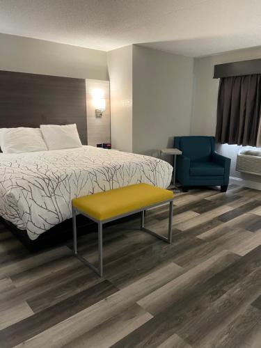 a hotel room with a bed and a yellow bench at HomeTown Inn and Suites Belle Plaine in Belle Plaine