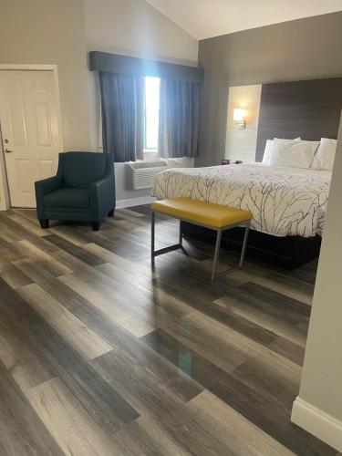 a hotel room with a bed and a chair at HomeTown Inn and Suites Belle Plaine in Belle Plaine