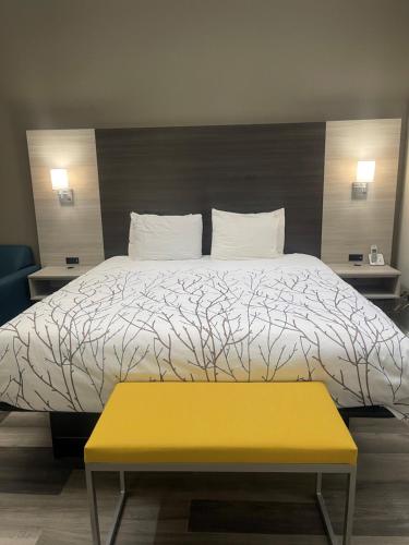 a bedroom with a bed and a yellow bench at HomeTown Inn and Suites Belle Plaine in Belle Plaine