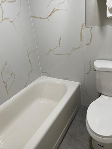 a bathroom with a white tub and a toilet at HomeTown Inn and Suites Belle Plaine in Belle Plaine
