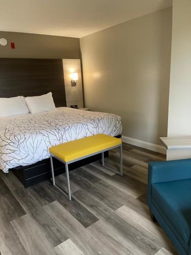 a hotel room with a bed and a yellow bench at HomeTown Inn and Suites Belle Plaine in Belle Plaine