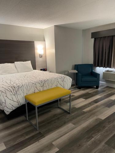 a hotel room with a bed and a yellow bench at HomeTown Inn and Suites Belle Plaine in Belle Plaine