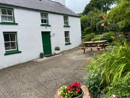 una casa bianca con una porta verde e un tavolo da picnic di Glenaan Cottage a Cushendall