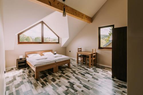 a bedroom with a bed and a desk and two windows at Szumny Dwór in Wetlina