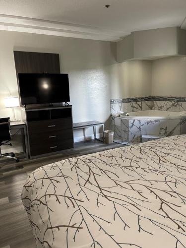 a hotel room with a bed and a flat screen tv at HomeTown Inn and Suites Belle Plaine in Belle Plaine