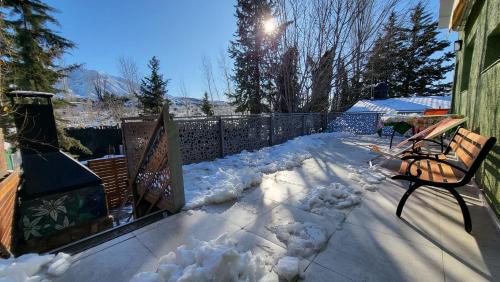 a snow covered patio with a bench and a fence at Cabaña Pica Piedra in Mendoza