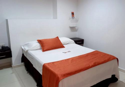 a bedroom with a bed with an orange pillow on it at Hotel San Lorenzo in Bucaramanga