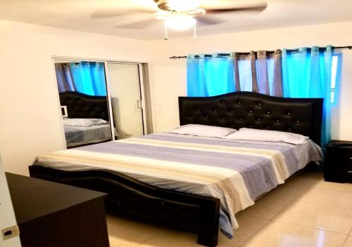 a bedroom with a large bed with blue curtains at Bello y comodo apartment , residencial con piscina, seguridad las 24 Horas in Licey al Medio