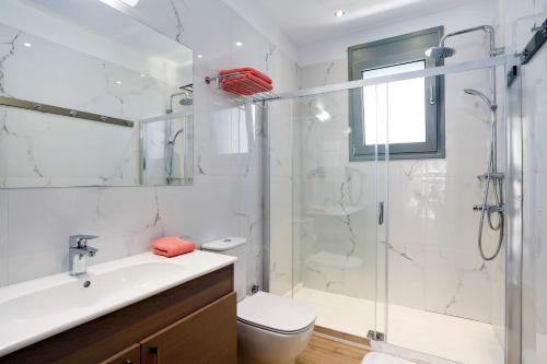 a bathroom with a shower and a toilet and a sink at Villa Paleos Hillside by Villa Plus in Ialysos