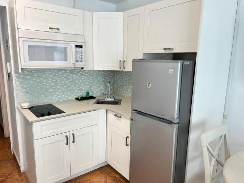 a kitchen with white cabinets and a stainless steel refrigerator at Ocean Front Units at Miami Beach in Miami Beach
