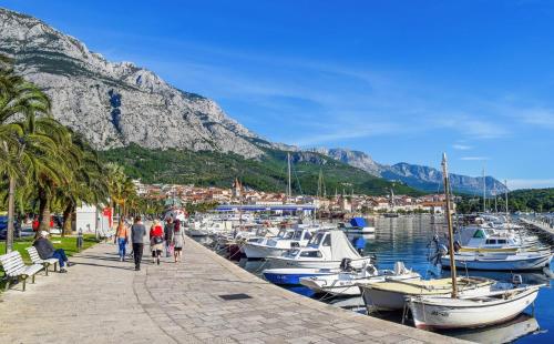 a group of people walking along a dock with boats at Old town Makarska apartments - central square in Makarska