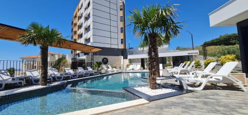 a swimming pool with white chairs and palm trees at SeaView Apartment & Pool in Ulcinj