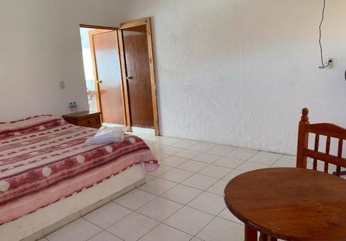 een slaapkamer met een bed en een houten tafel bij Hotel Puerto Villamar in Tepoztlán