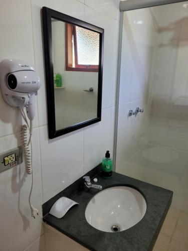 a bathroom with a sink and a mirror and a shower at Recanto da Natureza- Chalé in Gonçalves