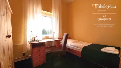 a bedroom with a bed and a desk and a window at Triskele Haus - Ökologisches Gästehaus der Heilstätte Strelitz in Neustrelitz