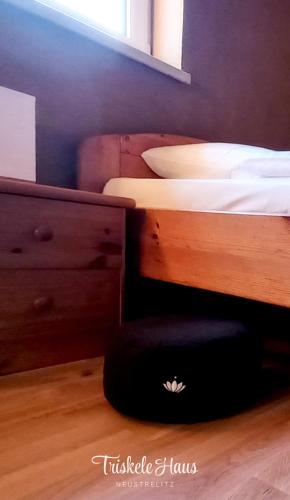 a bedroom with a bed with a wooden dresser and a bedskirts at Triskele Haus - Ökologisches Gästehaus der Heilstätte Strelitz in Neustrelitz