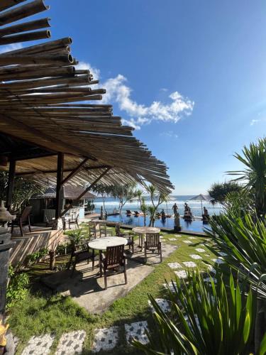 a patio with tables and umbrellas next to the ocean at Twilight Ceningan in Nusa Lembongan