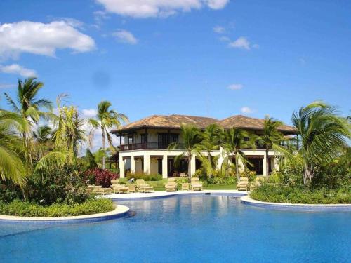 a house with a swimming pool in front of a house at 3 Bedroom Villa in Hacienda Pinilla in Tamarindo