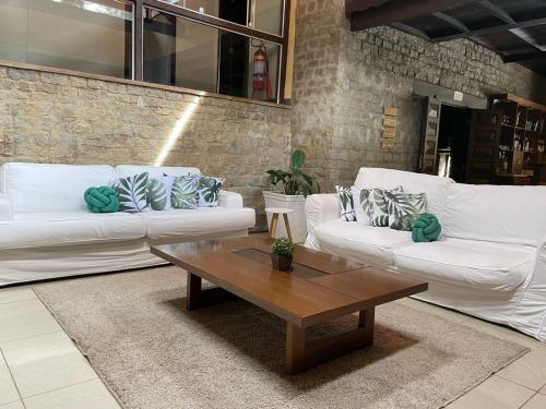 a living room with white couches and a coffee table at Pousada Cozy House in Itaipava